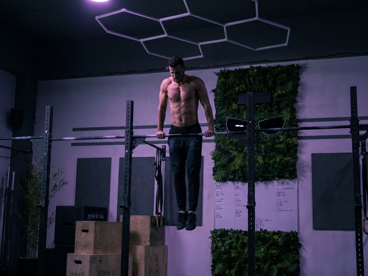 Athlète en haut d'un bar muscle-up, salle Devil Performance